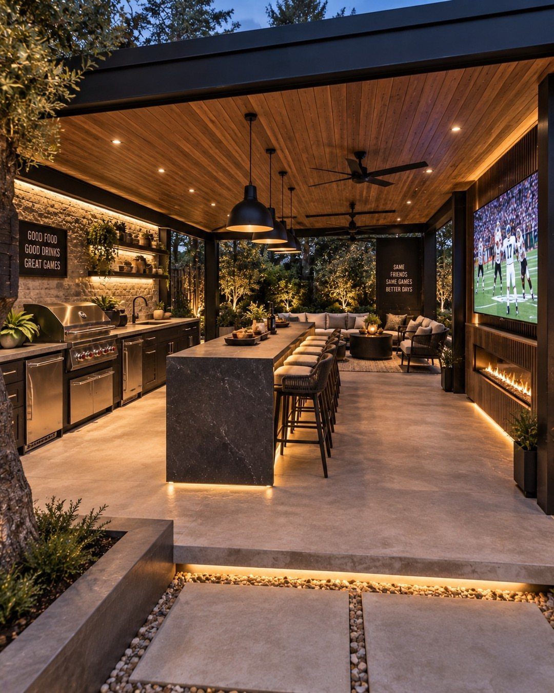Modern outdoor kitchen with a long dark stone island, bar stools, and stainless steel appliances.