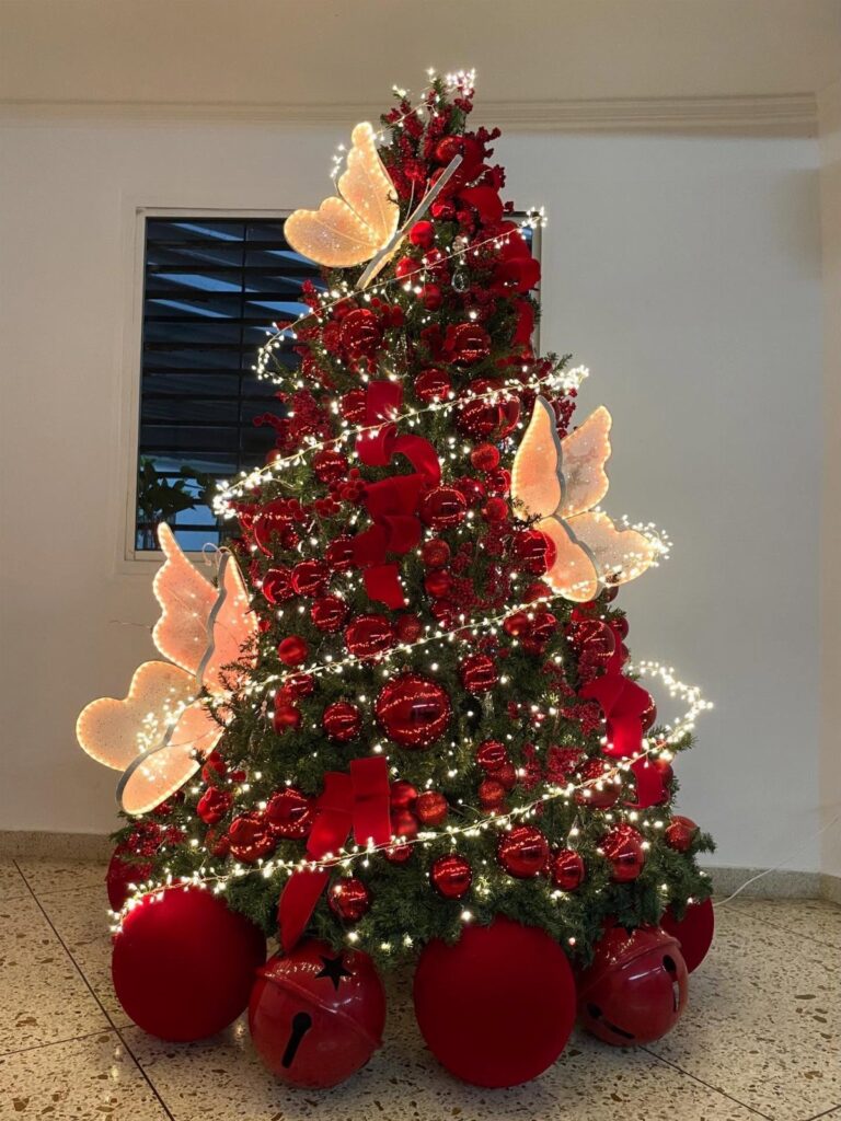 A decorated Christmas tree with red ornaments, white lights, and large butterfly decorations.