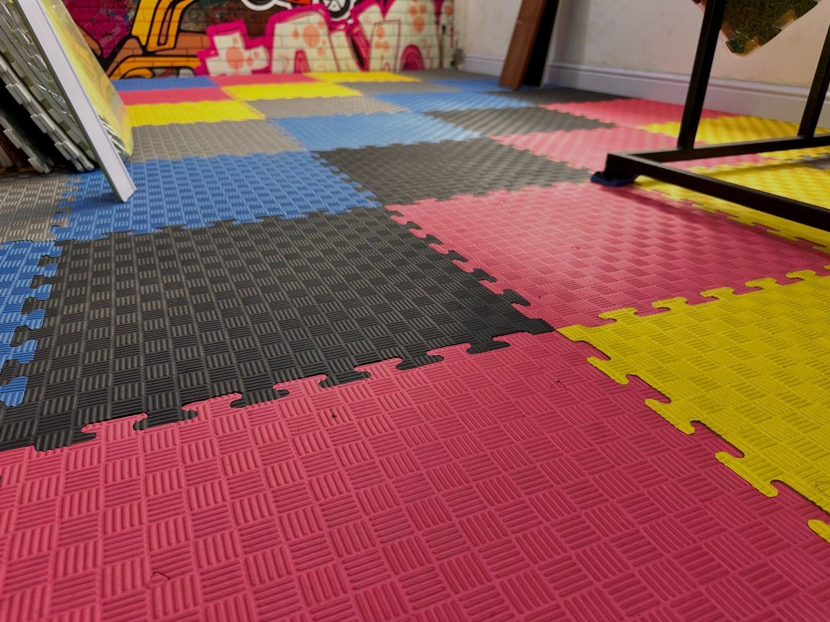 Colorful interlocking foam floor mats in pink, yellow, blue, and grey cover the ground.